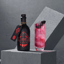 The Illusionist Gin FC Bayern Muenchen Edition Bottle Next to Red Cocktail in a Glass